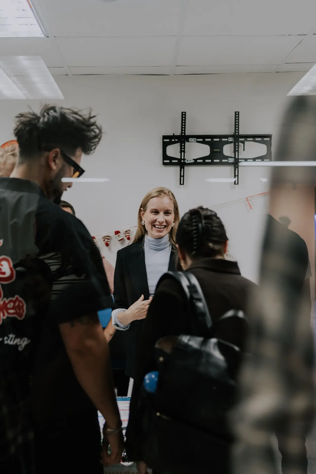 A smiling woman greets people in the church lobby